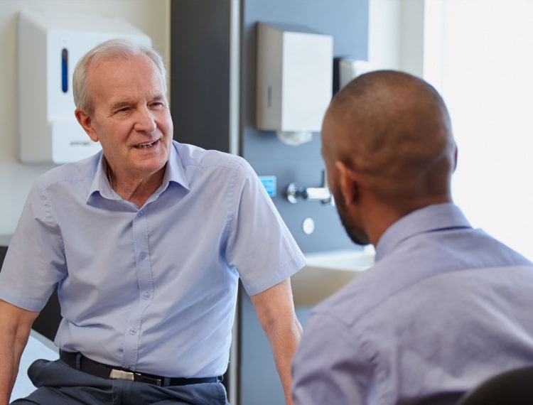 Advisor offering legal guidance to an older man with mesothelioma during a hopeful discussion
